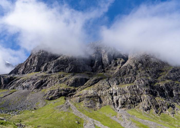 View of the north face of Ben Nevis in Scotland shrouded in cloud cover on a sunny spring day.