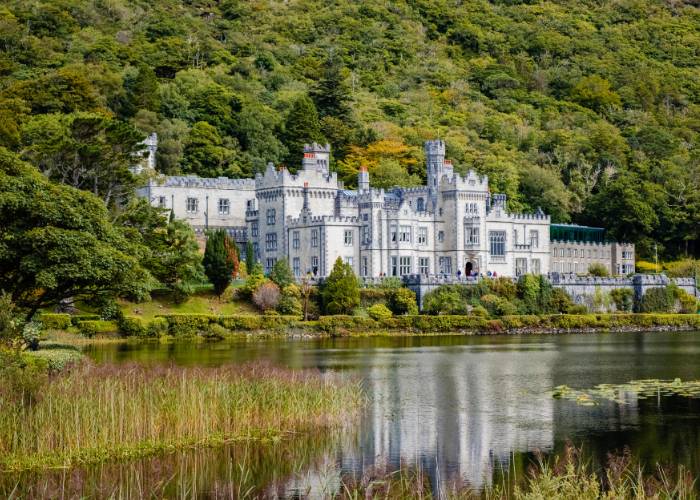 Kylemore Abbey, a majestic neo-Gothic castle reflected in the calm waters of Lake Pollacapall in Connemara, County Galway, Ireland. A building that embodies Victorian elegance