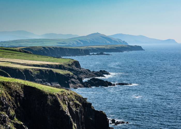 Panoramic view of Ireland's Dingle Peninsula, overlooking the Atlantic Ocean and a winding road along County Kerry's rugged coastline.