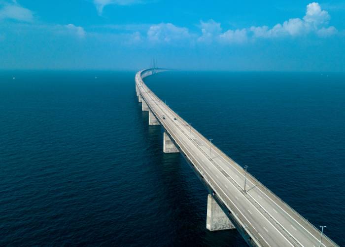 The Oresund Bridge, linking Copenhagen to Malmö on the Baltic Sea, with its clear, sunlit aerial view.