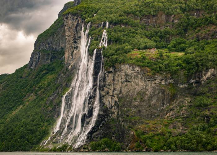 Vue aérienne des cascades des Sept Sœurs dévalant les falaises abruptes du Geirangerfjord, entourées par les montagnes majestueuses des Alpes de Sunnmøre en Norvège