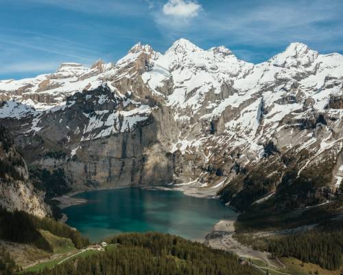 View of Lake Oeschinen in Switzerland, an alpine lake in the Swiss mountains near Kandersteg, surrounded by snow-capped peaks and lush green forests