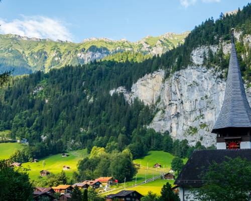 Panoramic view of the Lauterbrunnen valley in the Bernese Alps, Switzerland. The verdant valley is framed by sheer cliffs and snow-capped peaks