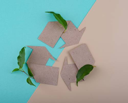 Flèches en carton recyclé symbolisant l’économie circulaire et la durabilité avec des feuilles vertes - Tourisme écoresponsable et recyclage